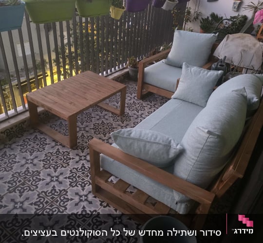 מרפסת עם עציצים, כורסאות ושולחן עץ.